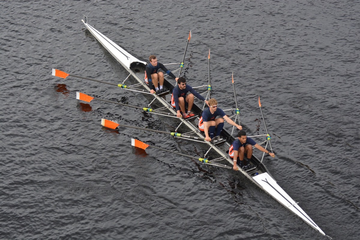 A quad scull seen from above, oars fanned out over dark water