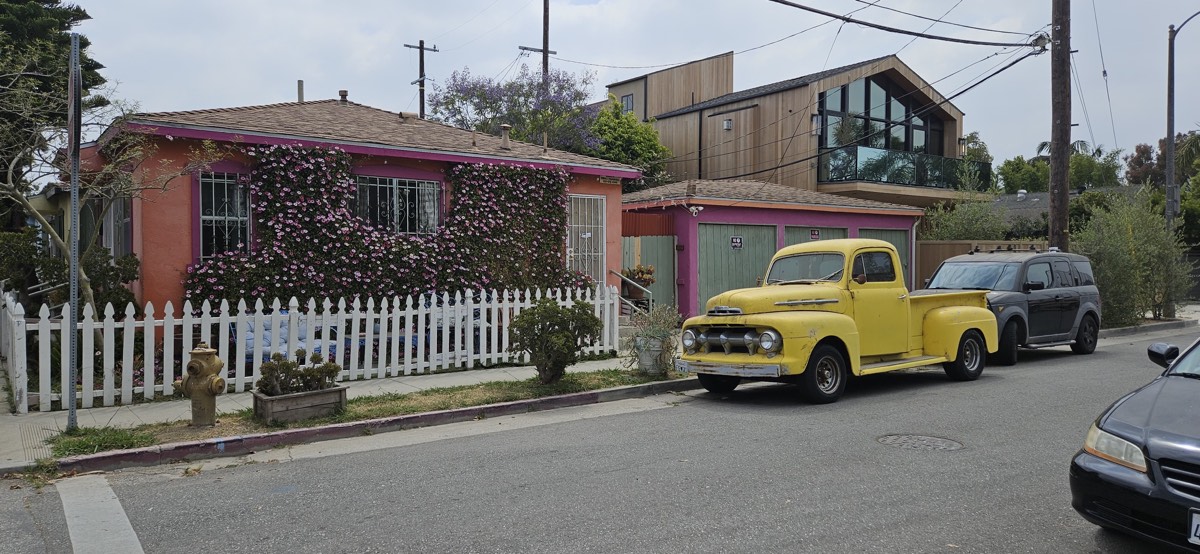 A pink cottage with a flower wall and a vintage yellow pickup truck
